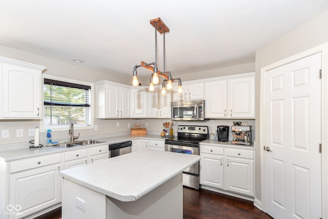 kitchen with stainless steel appliances, a kitchen island, a sink, and white cabinetry