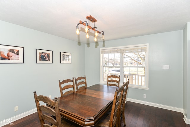 dining space with dark wood-style floors, a chandelier, and baseboards