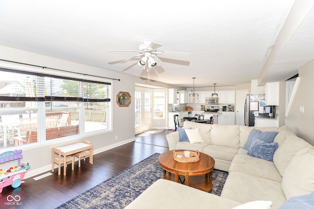 living area with a ceiling fan, dark wood-style flooring, and baseboards