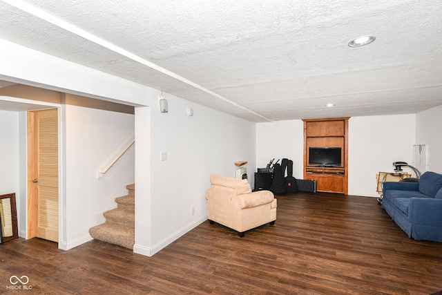 living room featuring a textured ceiling, dark wood-type flooring, stairway, and baseboards