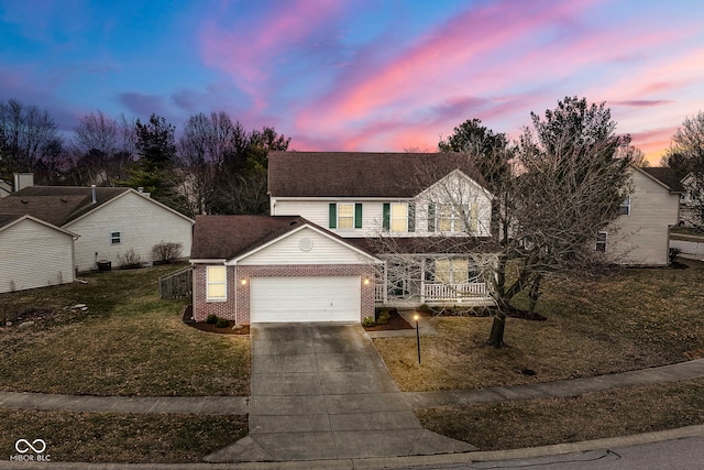 traditional-style home featuring a porch, a yard, concrete driveway, an attached garage, and brick siding