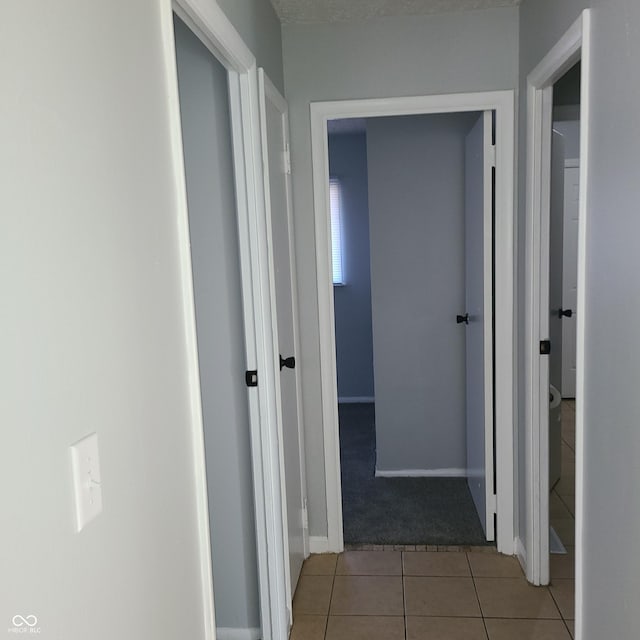 corridor featuring light tile patterned floors and baseboards