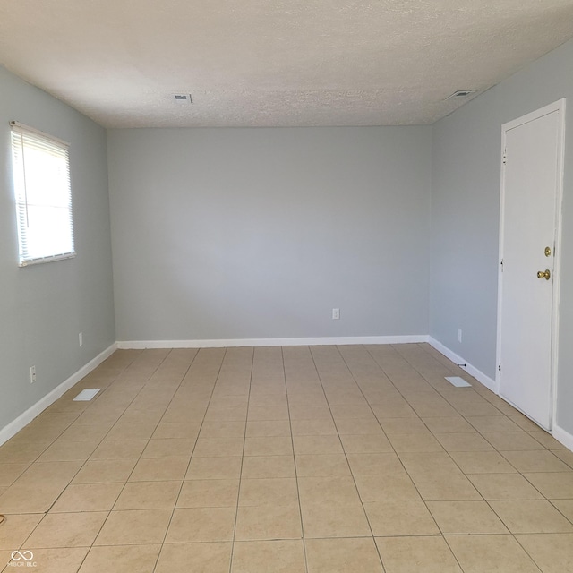 unfurnished room featuring visible vents, a textured ceiling, and baseboards