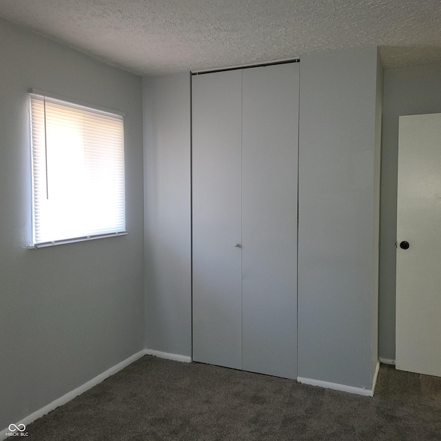 unfurnished bedroom featuring a textured ceiling, a closet, carpet, and baseboards