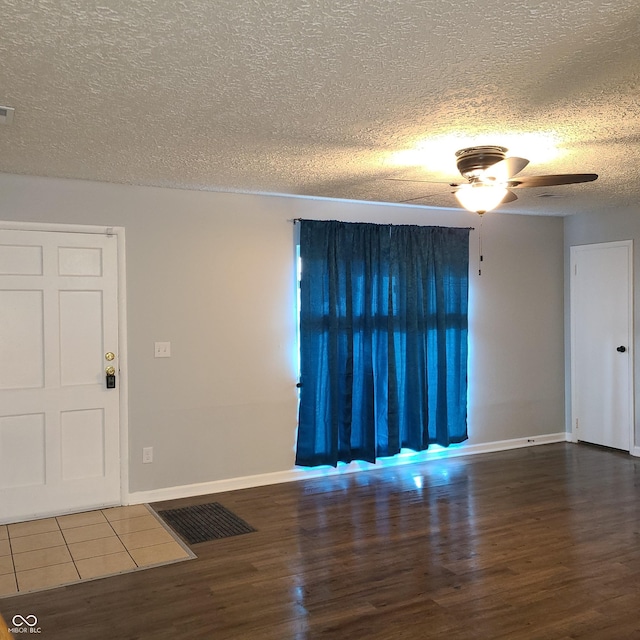 interior space featuring a ceiling fan, a textured ceiling, baseboards, and wood finished floors