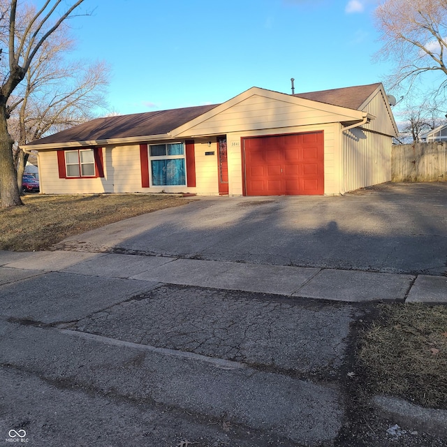 view of front facade with aphalt driveway, an attached garage, and fence