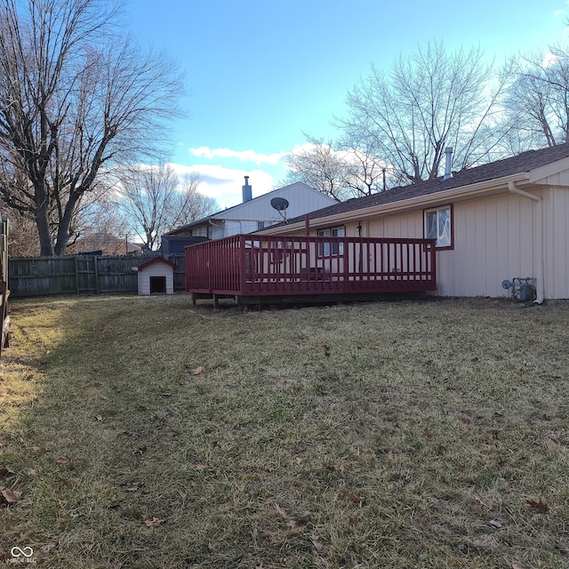 view of yard featuring a deck, a shed, an outdoor structure, and fence