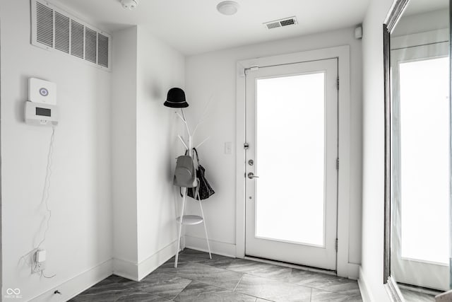 doorway with marble finish floor, visible vents, and baseboards