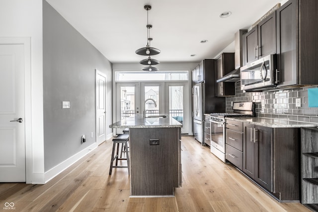 kitchen featuring stainless steel appliances, a sink, light wood finished floors, and decorative backsplash