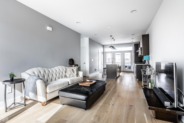 living area featuring light wood finished floors, recessed lighting, baseboards, and french doors