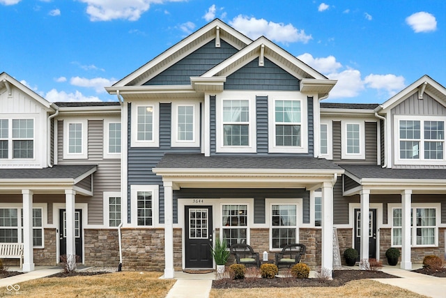 multi unit property featuring stone siding, a porch, and roof with shingles