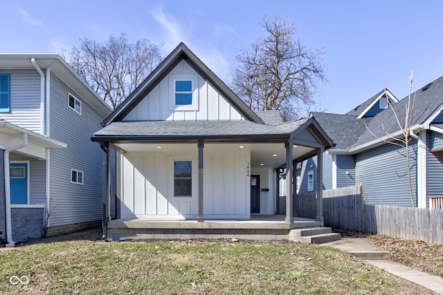 view of front of property featuring fence, covered porch, board and batten siding, and roof with shingles