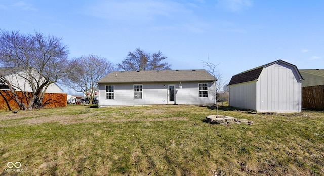 rear view of house featuring a gambrel roof, an outbuilding, a storage unit, fence, and a yard