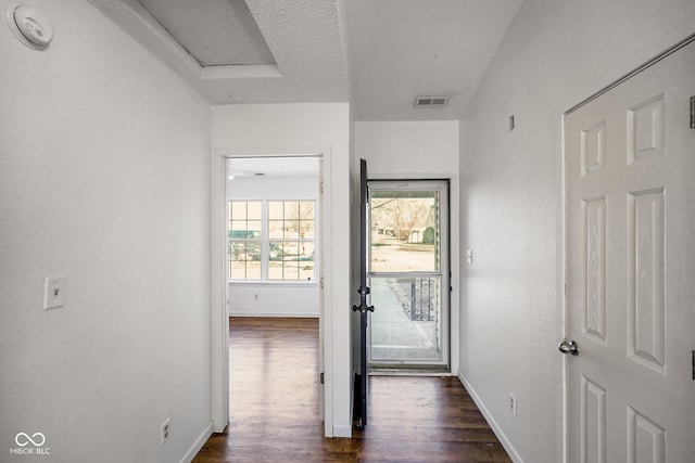 interior space with visible vents, dark wood-type flooring, attic access, a textured ceiling, and baseboards