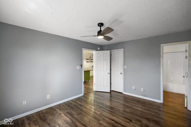 unfurnished bedroom with a ceiling fan, dark wood-style flooring, a textured ceiling, and baseboards