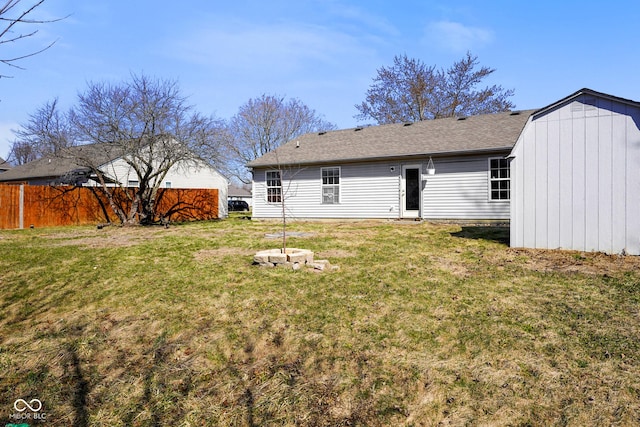 back of property with a yard, roof with shingles, and fence