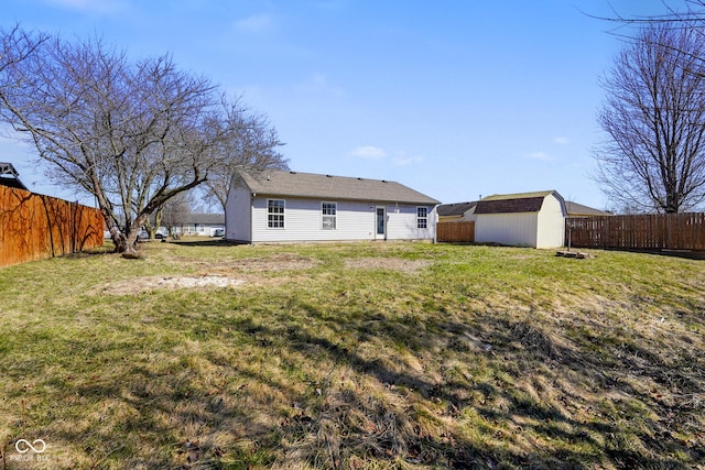 rear view of property with a yard, a fenced backyard, an outdoor structure, and a storage unit