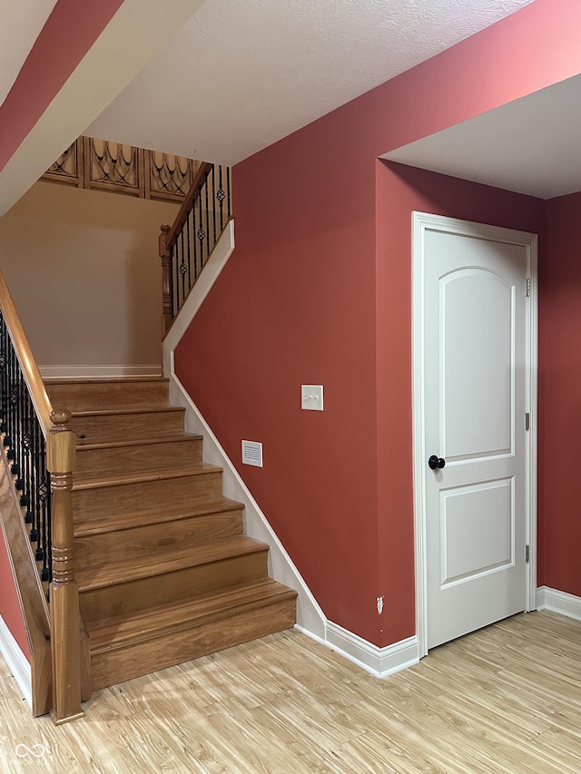 stairway with wood finished floors and baseboards