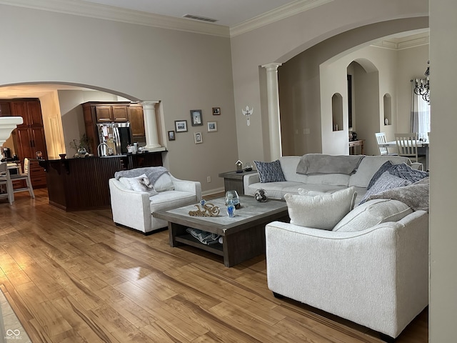 living area with light wood-style flooring, visible vents, and ornamental molding