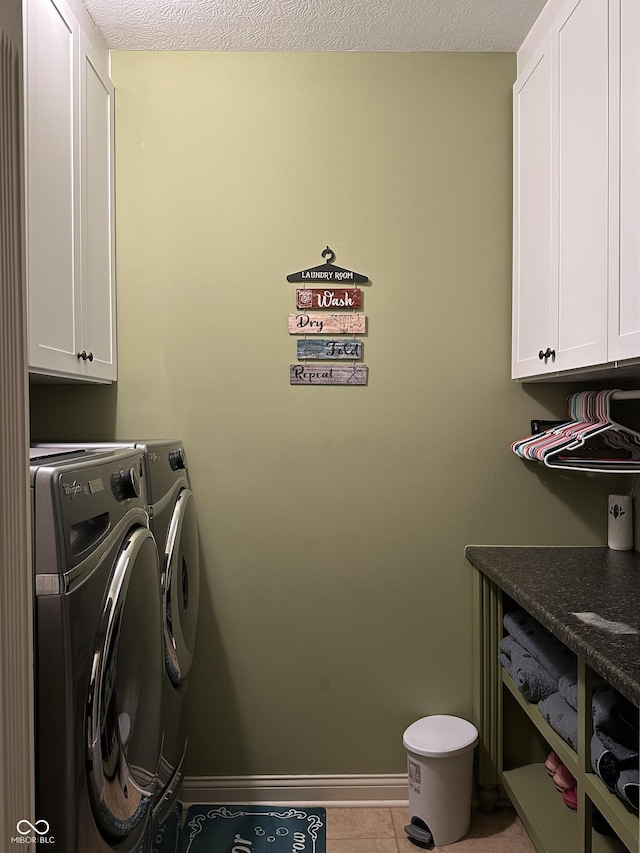 laundry area with cabinet space, baseboards, a textured ceiling, separate washer and dryer, and light tile patterned flooring