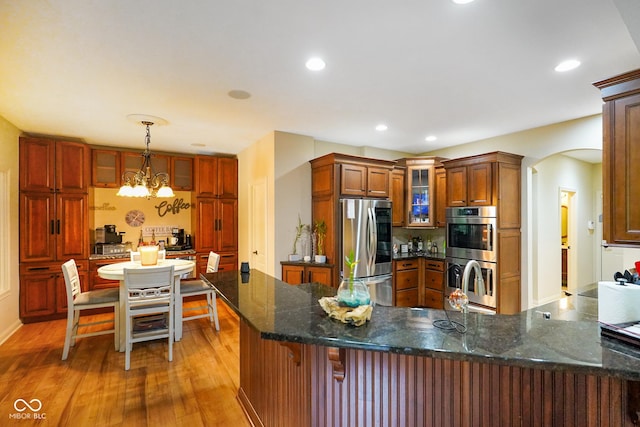286 S Woodridge Dr, Pittsboro, IN 46167 - kitchen with stainless steel appliances, arched walkways, light wood-type flooring, glass insert cabinets, and a chandelier