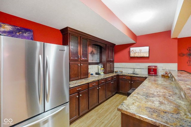 286 S Woodridge Dr, Pittsboro, IN 46167 - kitchen featuring freestanding refrigerator, a sink, a peninsula, light wood-style flooring, and glass insert cabinets
