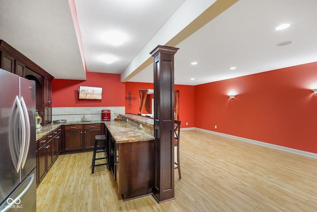 286 S Woodridge Dr, Pittsboro, IN 46167 - kitchen with freestanding refrigerator, light wood finished floors, a breakfast bar, ornate columns, and light stone counters