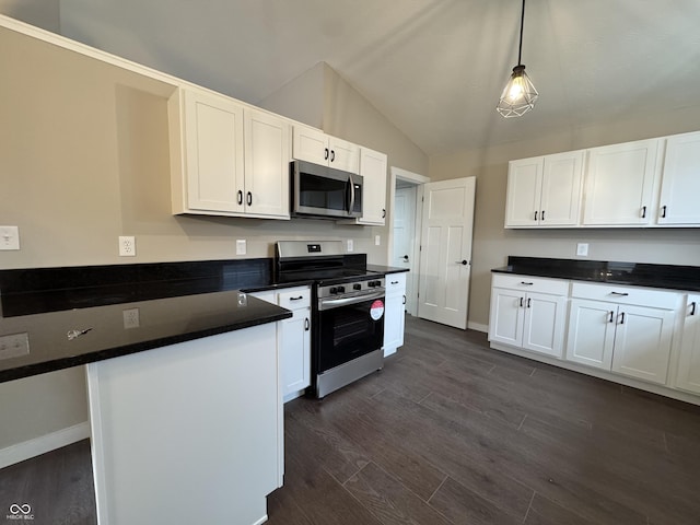 kitchen featuring dark countertops, appliances with stainless steel finishes, a peninsula, vaulted ceiling, and white cabinetry