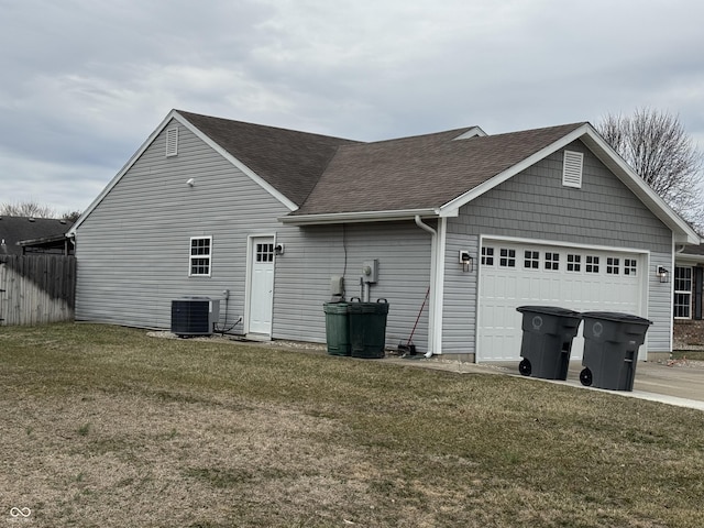 view of side of home featuring central air condition unit, a shingled roof, a lawn, a garage, and driveway