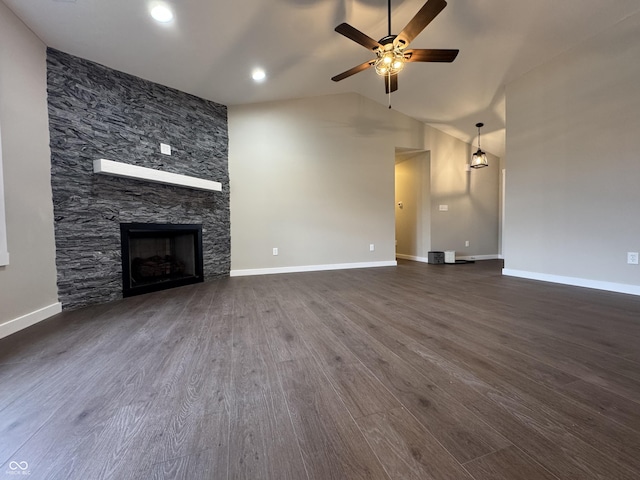 unfurnished living room with a stone fireplace, dark wood-style flooring, a ceiling fan, baseboards, and vaulted ceiling