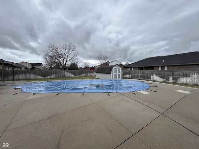 view of swimming pool featuring a storage shed, a fenced backyard, a patio area, and a fenced in pool