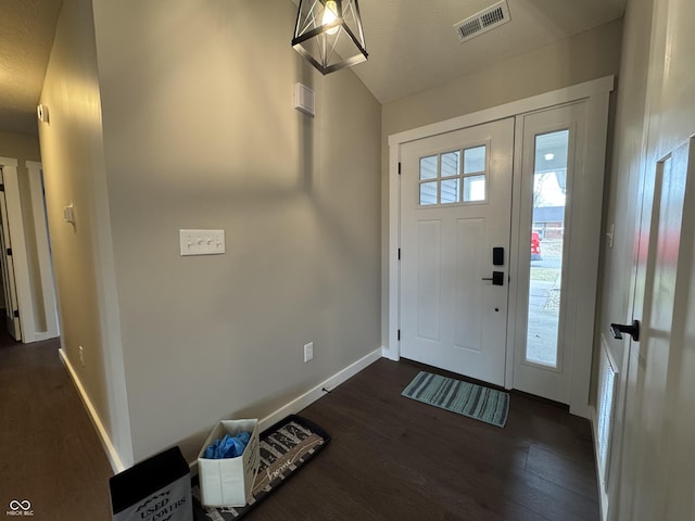 foyer entrance with dark wood-type flooring, visible vents, and baseboards