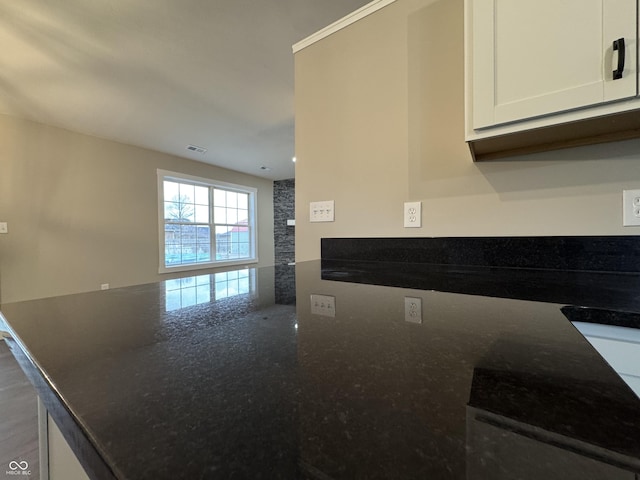 kitchen with visible vents, white cabinets, a peninsula, and dark stone countertops