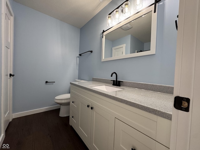 half bath featuring toilet, baseboards, wood finished floors, and vanity