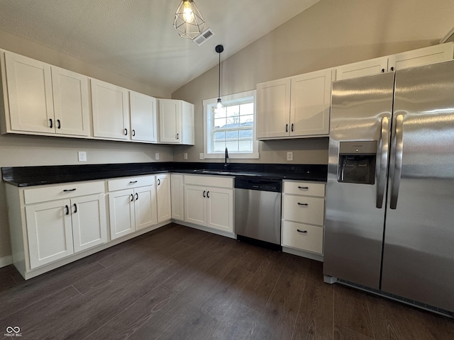 kitchen featuring lofted ceiling, appliances with stainless steel finishes, dark countertops, and dark wood-style floors