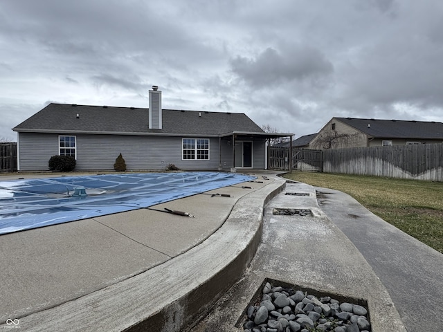 rear view of house with a patio area, a chimney, fence, and a fenced in pool