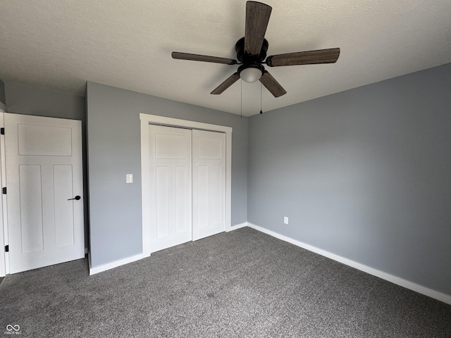 unfurnished bedroom featuring a textured ceiling, a closet, dark carpet, and baseboards