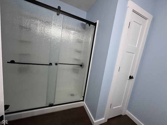 bathroom with a shower stall, baseboards, and wood finished floors