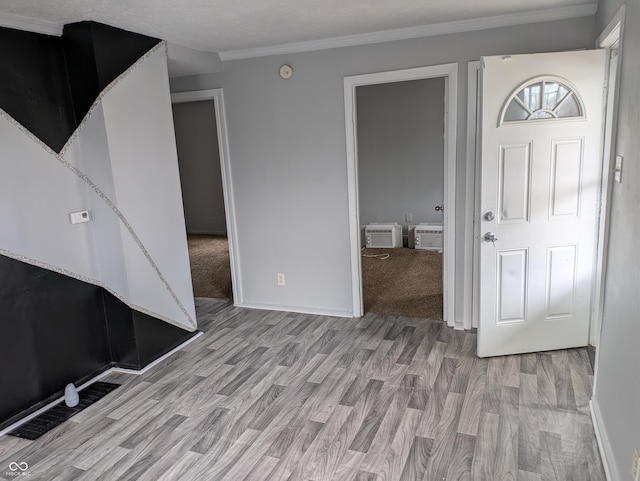 interior space featuring baseboards, an AC wall unit, light wood finished floors, and crown molding