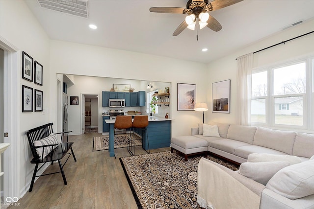 living area with light wood-style flooring, visible vents, and recessed lighting