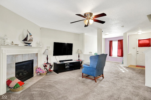 living room with carpet, a fireplace, a ceiling fan, and a textured ceiling