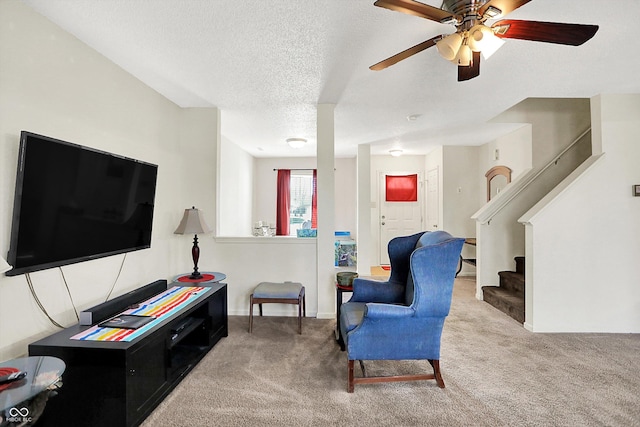 sitting room featuring a ceiling fan, carpet, stairway, and a textured ceiling