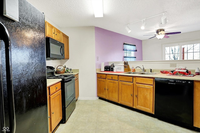 kitchen featuring light countertops, brown cabinetry, a sink, a textured ceiling, and black appliances