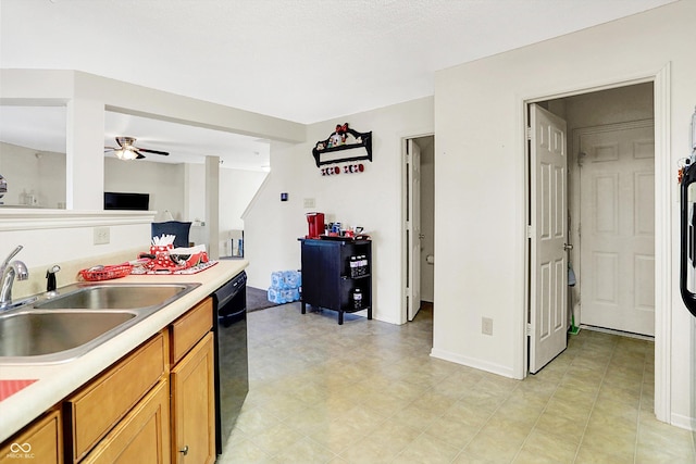 kitchen with brown cabinetry, black dishwasher, light countertops, and a sink