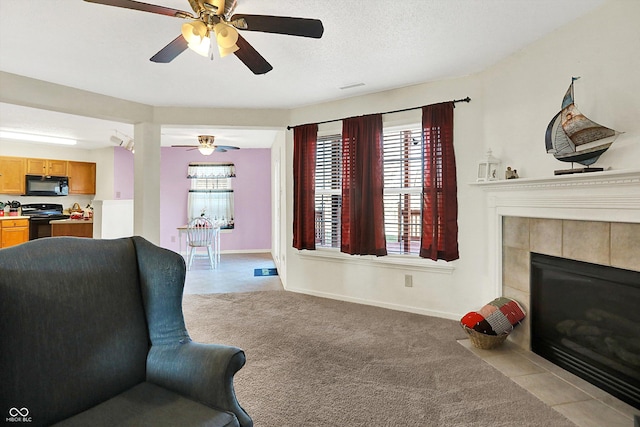 living room featuring a tile fireplace, baseboards, a textured ceiling, and light colored carpet