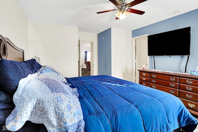 bedroom with a textured ceiling, visible vents, and a ceiling fan