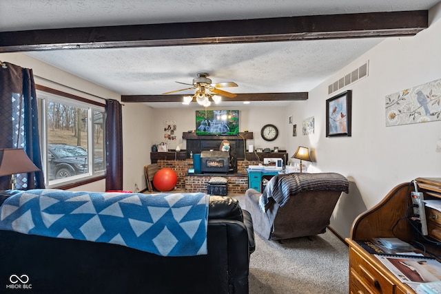 carpeted living room with a brick fireplace, beam ceiling, visible vents, and a textured ceiling