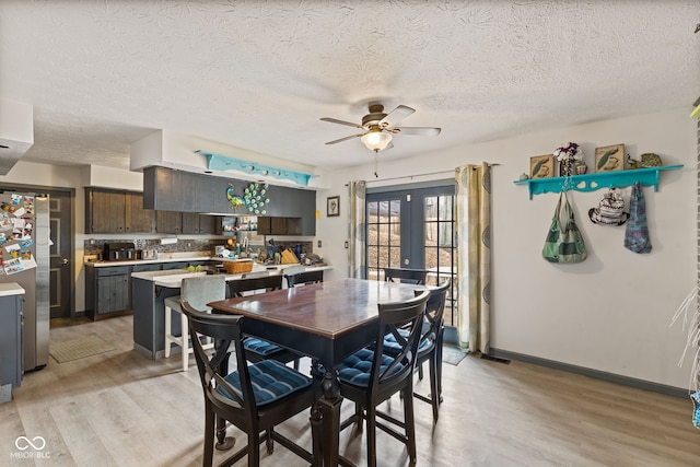 dining room featuring french doors, light wood-style floors, ceiling fan, a textured ceiling, and baseboards