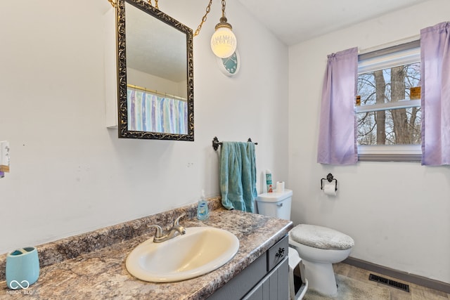 full bathroom with toilet, baseboards, visible vents, and vanity