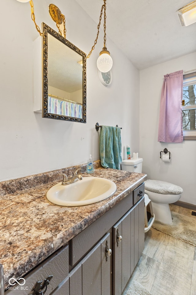 full bath with toilet, vanity, and baseboards